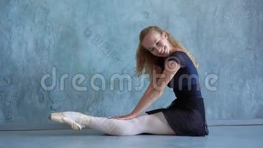 这个女孩在芭蕾舞学校的工作室里热身。 金发美女在镜头前微笑.. 年轻人